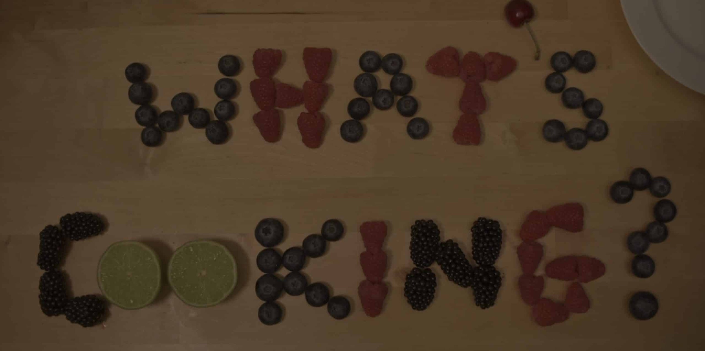 The words “What’s cooking?” spelt out in berries and fruit