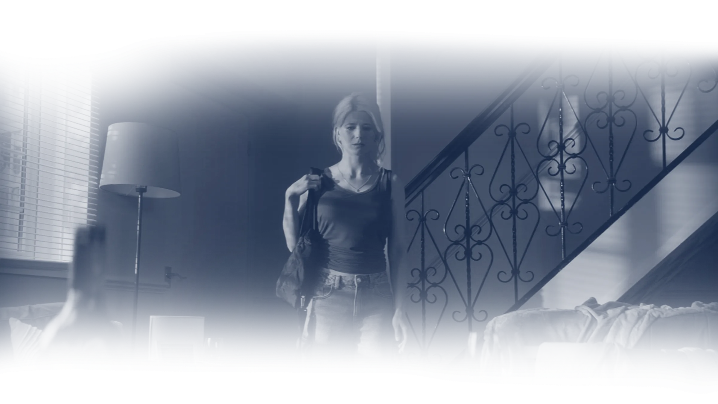 A woman walking through a dim hallway in a still from the opening of Retracing Jemma